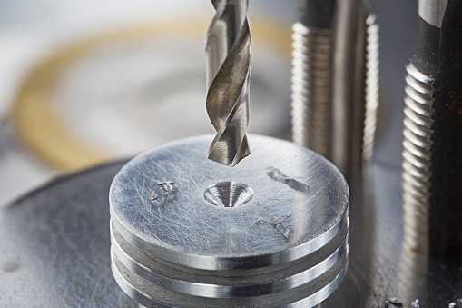 metal drill bit make holes in aluminium radiator on industrial drilling machine. Metal work industry.