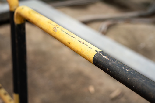 Close-up at the metal fence structure which is painted in yellow-black color, using to barricade danger working area. Industrial equipment object photo, Selective focus.
