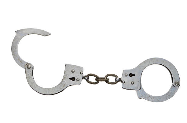 Metal handcuffs with one half open on a white surface stock photo