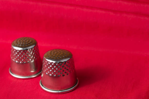 Metal sewing thimbles on bright red fabric background stock photo