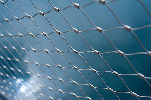 Metallic net with blue background Metallic chain fence link net with blue defocused background. Tilt-shift lens used used to accent the freedom concept and emphasize the attention on them. linkage effect stock pictures, royalty-free photos & images
