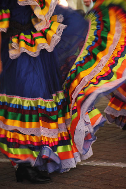 A section of a Mexican dresser's dress during a Mexican celebration. Like all folk dancing, traditional Mexican dances provide a glimpse into the culture of the region. Not only do these dances from Mexico express the rhythms of the music, but also the vital colors woven into Mexican clothing and decoration.