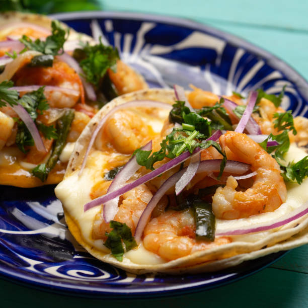 Mexican food. Shrimp tacos with melted cheese and poblano pepper called gobernador on turquoise background. stock photo