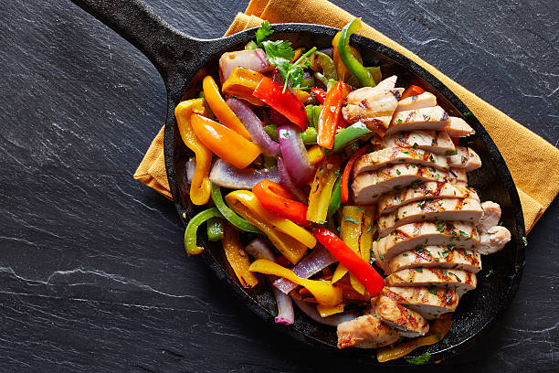 mexican grilled chicken fajitas in iron skillet mexican grilled chicken fajitas in iron skillet shot from overhead on slate mexican culture photos stock pictures, royalty-free photos & images