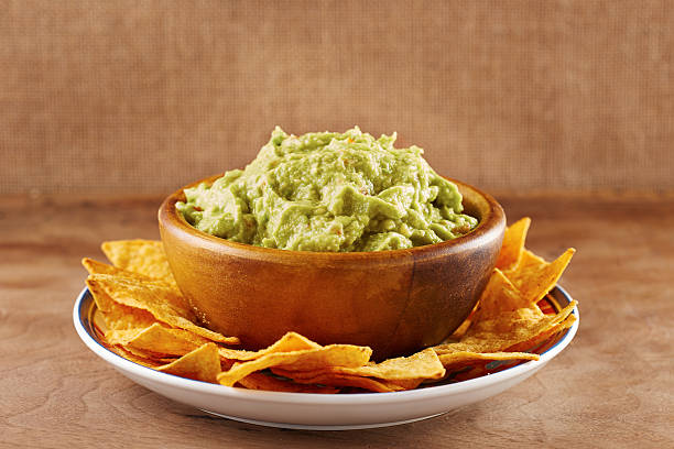 Mexican nachos with handmade guacamole sauce Mexican nachos with handmade guacamole sauce on wooden table guacamole stock pictures, royalty-free photos & images
