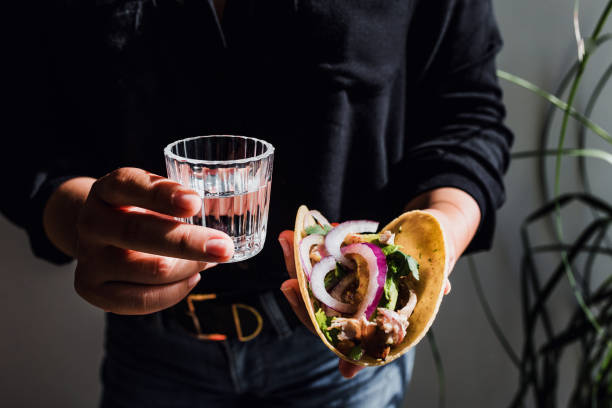 Mexican woman hands holding tacos and mezcal shot traditional food in Mexico city stock photo