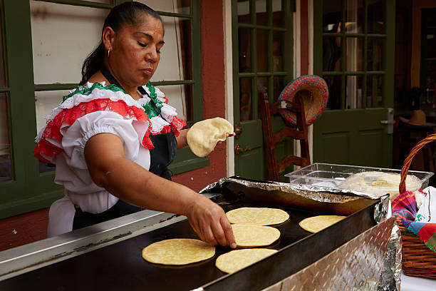 Mexican Woman Prepares Tortillas On Open Griddle stock photo