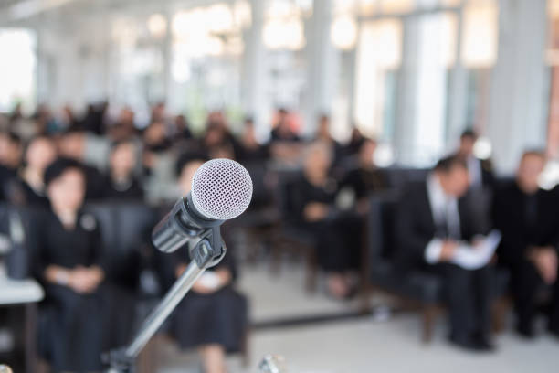 Microphones on the funeral podium and people wearing black in the church stock photo