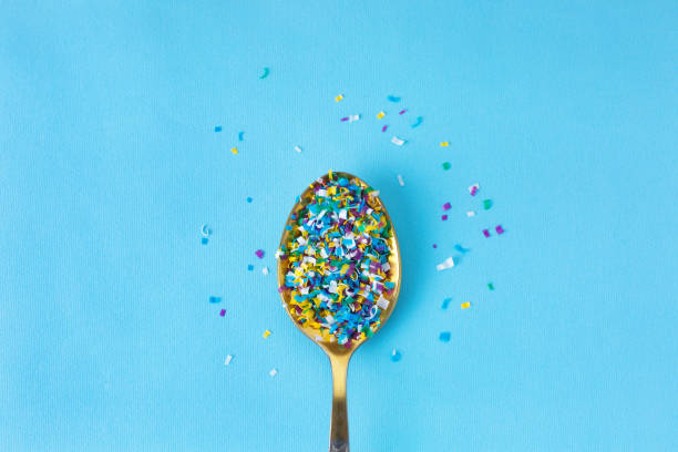 Microplastic in a spoon on blue background. microplastic in water and food. Microplastic problem. Dangerous additives. Toxic substances. stock photo