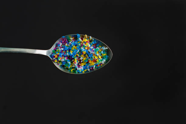 Microplastic in spoon on black background . Threat to human health and environment Dangerous additives Toxic substances. stock photo