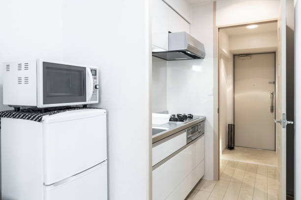 Microwave and refrigerator placed next to the kitchen cabinet in a small new apartment room stock photo