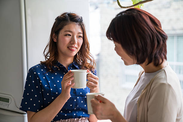 Mid adult daughter and senior mother talking while having coffee Mid adult daughter and senior mother talking while having coffee asian mother talking with daughter stock pictures, royalty-free photos & images