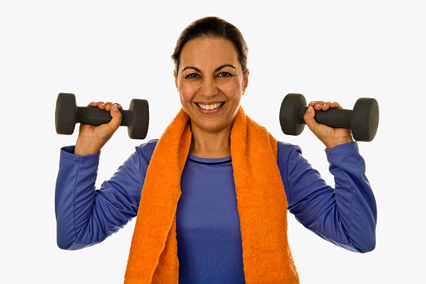 Mid adult female holding weights wearing workout attire stock photo