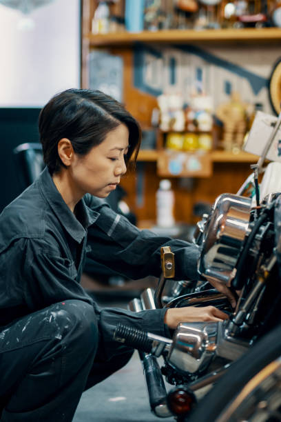 Mid adult female mechanic repairing a motorcycle in her small business garage. stock photo