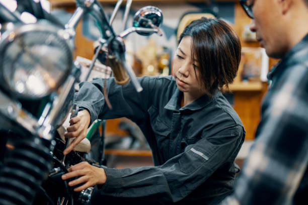 Mid adult female mechanic showing a motorcycle to a client stock photo
