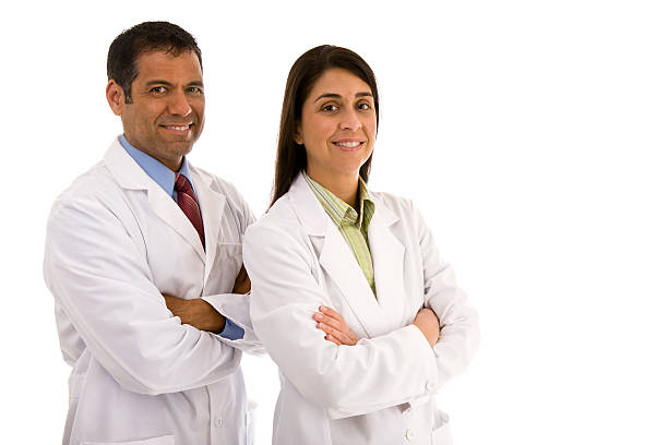 Mid adult male and female wearing lab coat arms crossed stock photo