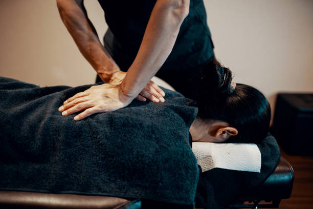 Mid adult male chiropractor treating a female patient stock photo