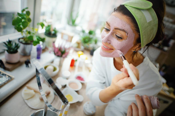 Mid adult woman applying facial mask. stock photo
