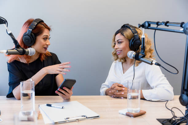 Mid adult woman interviews female guest for radio show stock photo