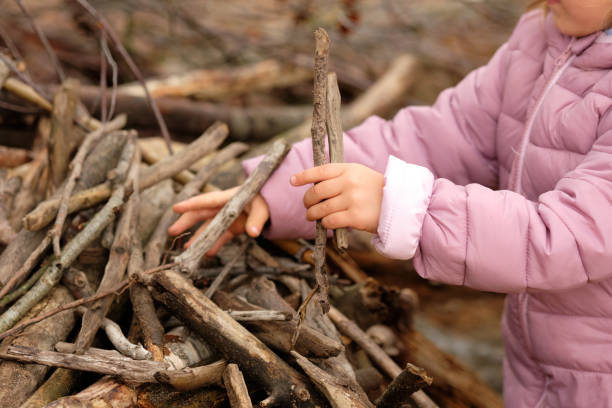 Mid section of child girl in warm clothing building something with sticks stock photo