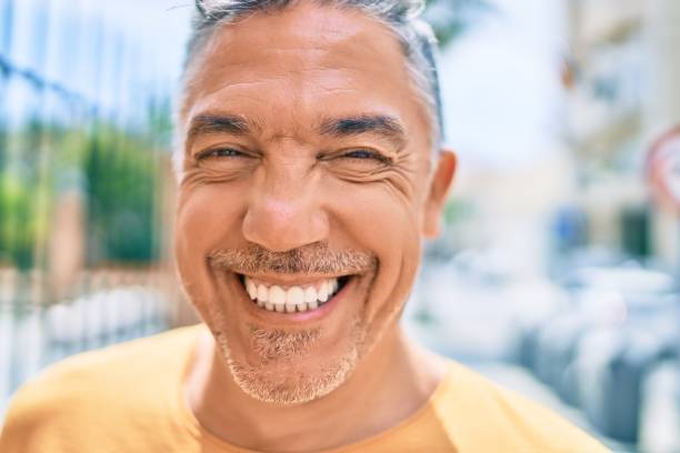 Middle age grey-haired man smiling happy walking at street of city. stock photo