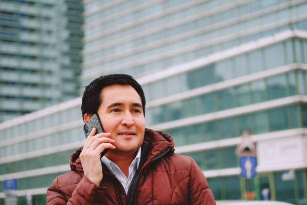 Middle aged asian man sitting on the bench with phone. stock photo