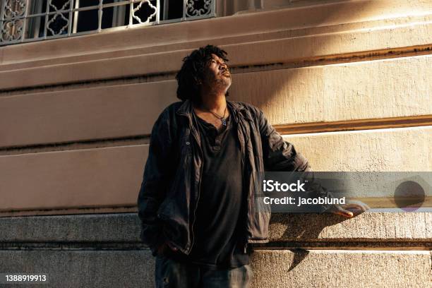 Middle aged homeless man looking up thoughtfully outdoors