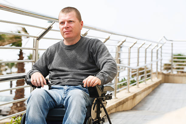 Middle aged man in wheelchair moving down ramp stock photo