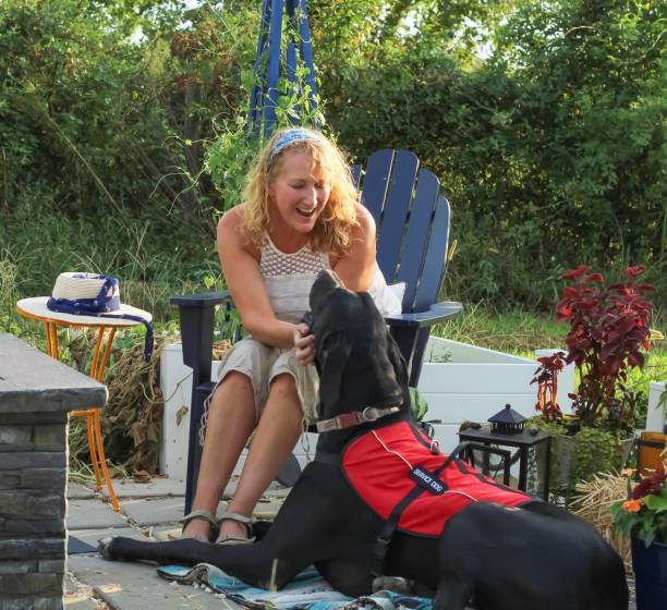 Middle aged woman with mobility issues is able to enjoy her garden patio outdoors with her Great Dane service dog helping her Middle aged woman with mobility issues is able to enjoy her garden patio outdoors with her Great Dane service dog helping her multiple sclerosis stock pictures, royalty-free photos & images