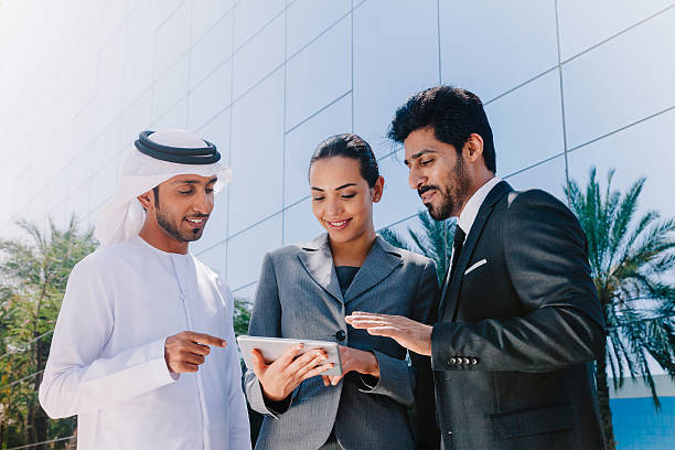Middle Eastern Businessmen and Businesswoman working with Digital Tablet Outdoor Three Middle Eastern business people with traditional and classic suit clothes working with Digital Tablet Pc outdoor middle eastern culture stock pictures, royalty-free photos & images
