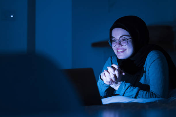Middle Eastern Girl Watching Video Using Laptop Hijabi Girl at home using Laptop to watch Social Media Viral Video streaming service stock pictures, royalty-free photos & images