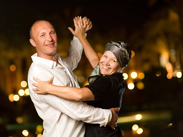 Middle-aged couple dancing waltz at night stock photo