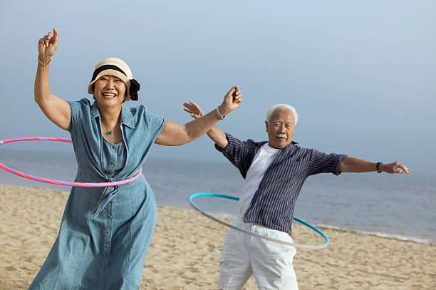 Middle-Aged Couple Hula Hooping Middle-Aged Couple Hula Hooping 50 59 years stock pictures, royalty-free photos & images