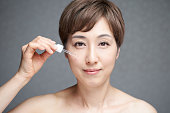 顔に美容エッセンスを塗る中年日本人女性