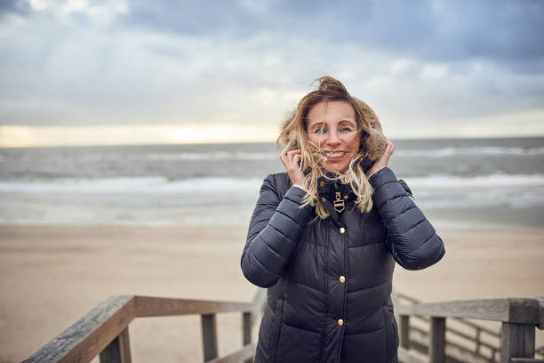 Photo of Middle-aged woman braving a cold winter day at the sea