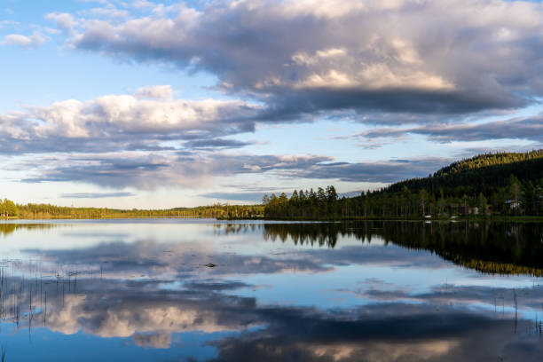 Midnight sun in Northern Sweden with calm dark sky and reflections in mountain lake. stock photo
