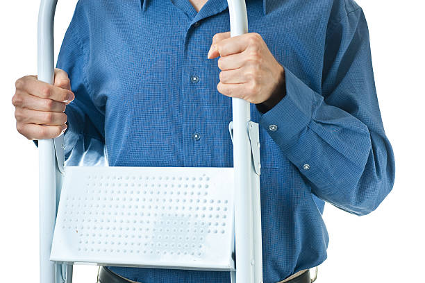 Mid-section of man in dress shirt holding step ladder stock photo
