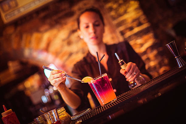 Midsection of young female bartender preparing cocktail in cocktail bar stock photo