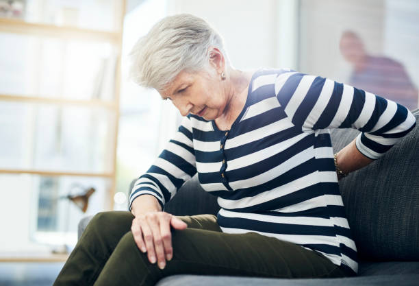 I might need to see a chiropractor Shot of a senior woman experiencing back pain at home osteoporosis photos stock pictures, royalty-free photos & images