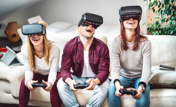Milenial people playing with vr glasses on sofa - Virtual reality and wearable tech concept with surprised friends having fun with headset goggles - Generation z digital trends - Focus on mid guy face stock photo