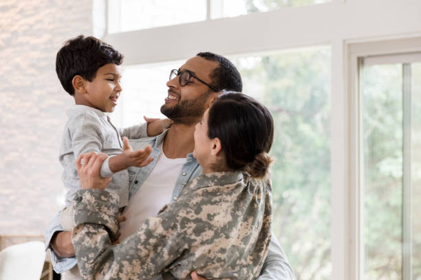 A military family is reunited An excited family welcomes home a returning soldier. The female soldier embraces her husband and young son. veterans returning home stock pictures, royalty-free photos & images