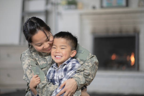 Military Mom Hugging Her Son A mother and her son are hugging in their living room. The mother is wearing a military uniform. filipino family stock pictures, royalty-free photos & images