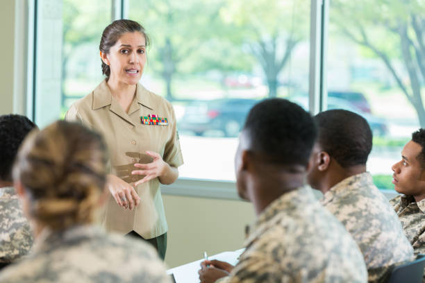 Military officer teaching class in military academy Confident mature Hispanic female officer teaches a class at a military academy. Students are attentively listening to her lecture. military colleges stock pictures, royalty-free photos & images