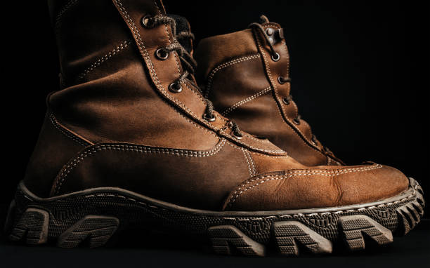 Military tactical boots standing. Photo of brown military tactical boots standing on black surface background profile view. infantry stock pictures, royalty-free photos & images