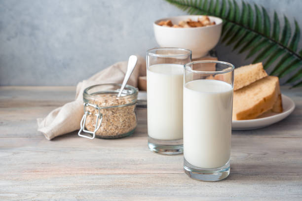Desayuno de leche, dos vasos de leche, avena y migas de pan sobre un fondo gris - foto de stock