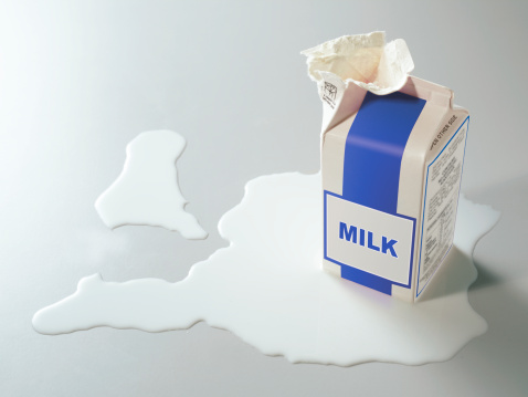 carton of milk opened with spilt milk around it
