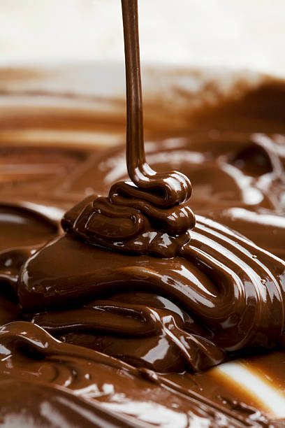 Milk chocolate being poured into bowl stock photo