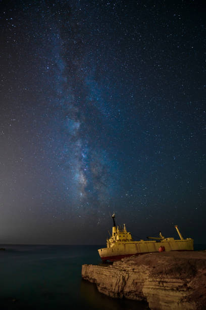 Milky Way and cargoship aground near sea shore stock photo