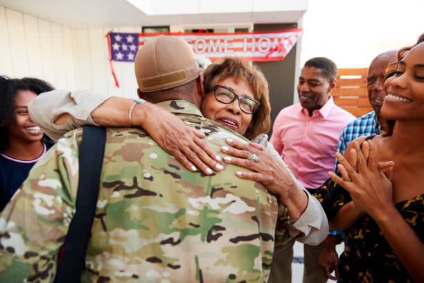 Millennial black soldier returning home to his family, embracing grandmother, back view  soldiers returning home stock pictures, royalty-free photos & images