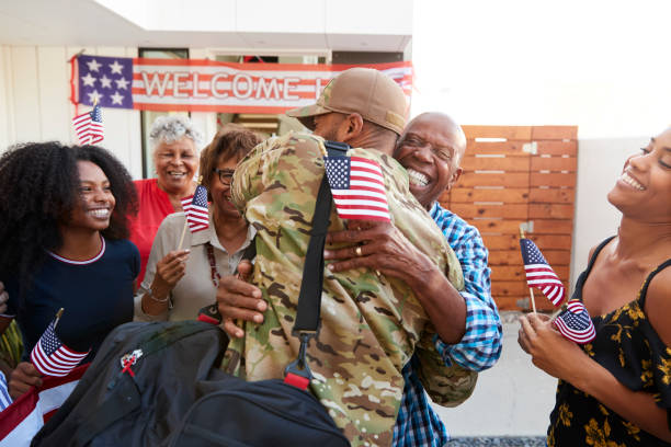 Millennial black soldier returning home to his family, embracing grandfather, back view  soldiers returning home stock pictures, royalty-free photos & images